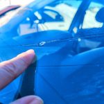 finger pointing to windshield chip