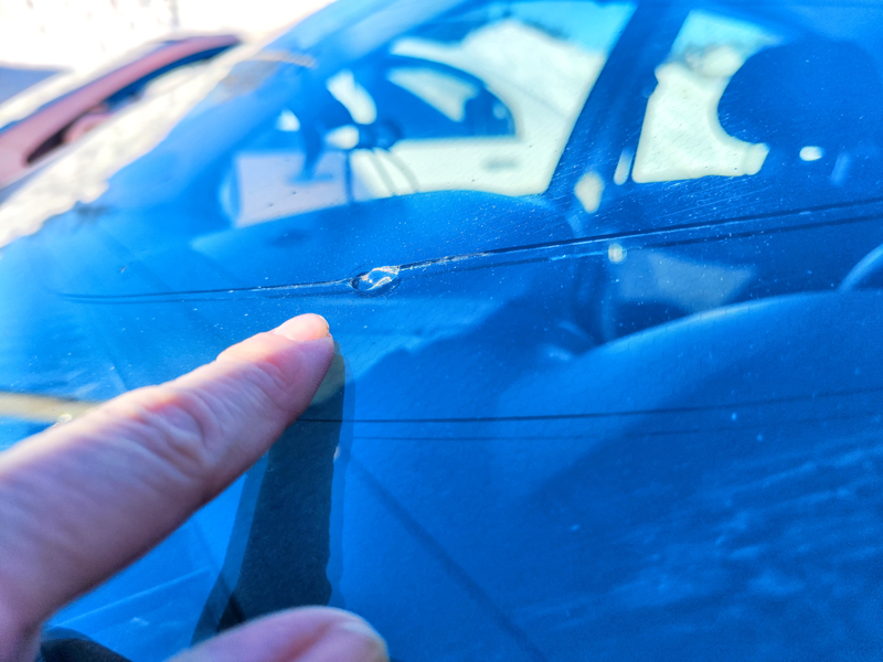 finger pointing to windshield chip