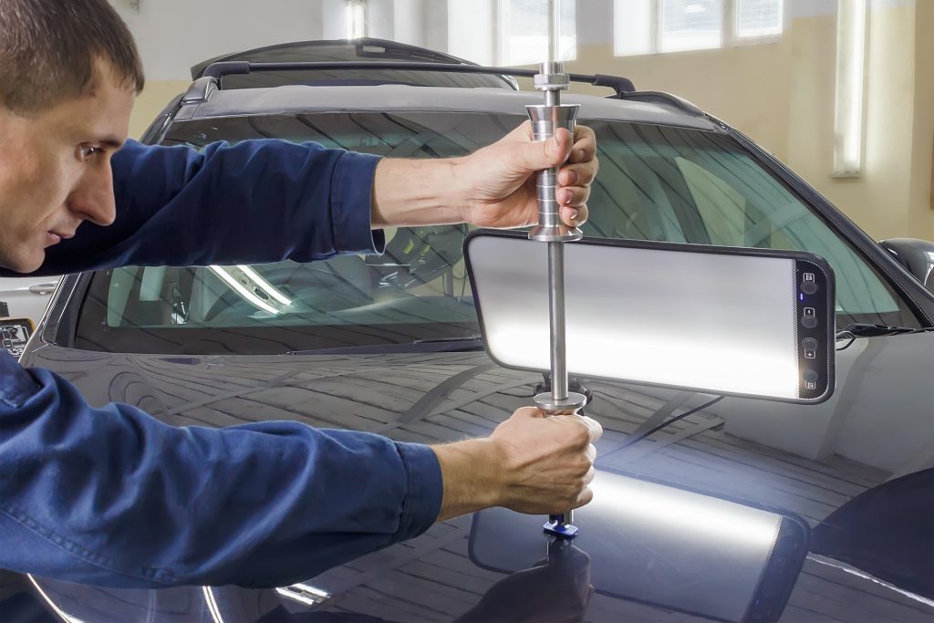 Dent repair technician removing dents from car