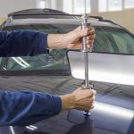 Dent repair technician removing dents from car